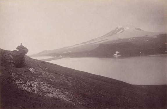 Dobová fotografie z roku 1883. Pohled na sopku Beerenberg, skalní útvar kamenné hlavy a ledovcovou lagunu.